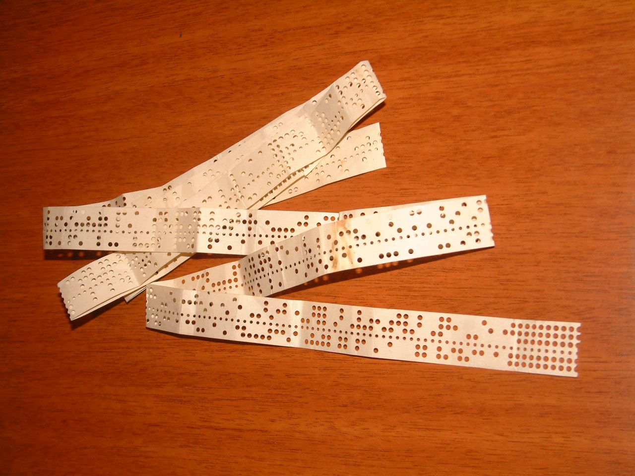 A piece of teletype tape with ITA2 encoded text punched on it.